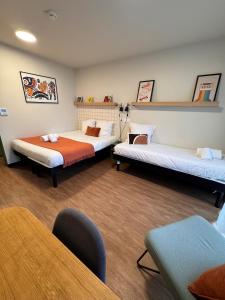 een kamer met twee bedden en een tafel en stoelen bij Hife Toulouse Sud Labège in Labège