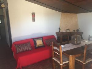 Una sala de estar con un sofá rojo y una mesa. en Casa La Cascada, en El Bosque
