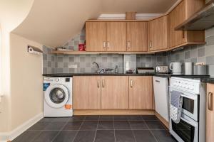 a kitchen with wooden cabinets and a washer and dryer at The Crow's Nest - Elie in Elie