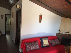un sofá rojo en la sala de estar con un reloj en la pared en Casa La Cascada, en El Bosque