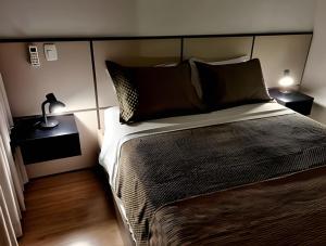 a bedroom with a bed and a lamp on a table at Gramado Loft 105 in Gramado