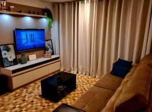 a living room with a couch and a flat screen tv at Gramado Loft 105 in Gramado