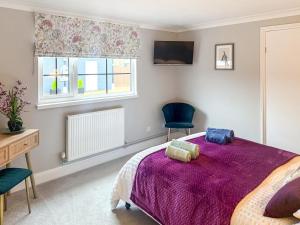 1 Schlafzimmer mit einem lila Bett und 2 Stühlen in der Unterkunft 2 Bed in Gimingham oc-h27869 in Trimingham