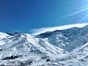 a snow covered mountain range with the sun in the sky at riad atlas imnane in Imlil
