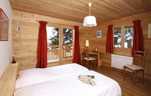 a bedroom with a bed and a desk and windows at Odalys Chalet La Muzelle in Les Deux Alpes