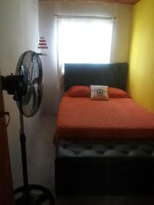 Schlafzimmer mit einem Bett, einem Ventilator und einem Fenster in der Unterkunft Los patos in Capilla del Monte