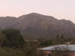 a mountain in the distance with a building and trees at Los patos in Capilla del Monte