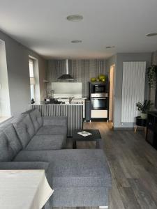 a living room with a couch and a kitchen at Le refuge de Villeroux in Vaux-sur-Sûre