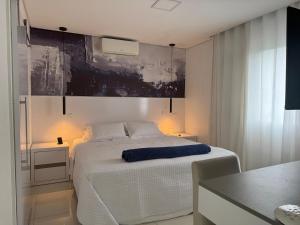une chambre avec un lit blanc et un tableau au mur dans l'établissement Linda Cobertura Pitangueiras, à Guarujá