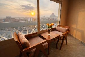 een kamer met een tafel, stoelen en een raam bij Zoom Pyramids View inn in Caïro