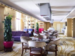 a restaurant with tables and chairs and a purple couch at Novotel Daqing Haofang in Daqing