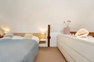 una camera da letto con un letto e un comò bianco di Räucherhäuschen a Fehmarn