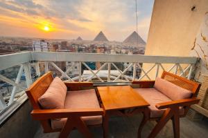 een tafel en stoelen op een balkon met piramides bij Zoom Pyramids View inn in Caïro