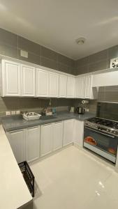 eine Küche mit weißen Schränken und einem Backofen in der Unterkunft روف جازان ذات التصميم الفندقي in Dschāzān