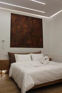 a bedroom with a white bed with a painting on the wall at Lūma Retreat in Kastoria