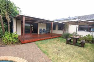 a house with a wooden deck with a table and an umbrella at African Oasis Morrocco in Somerset West
