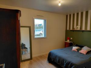 een slaapkamer met een bed, een raam en een spiegel bij Saint-Cast-Le-Guildo in Saint-Cast-le-Guildo