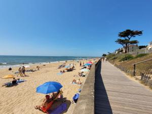 Eine Gruppe von Menschen am Strand in der Nähe einer Promenade in der Unterkunft L'Aigue Marine by TAH - Top emplacement & Parking in Pornichet