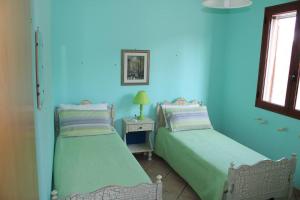 twee bedden in een kamer met blauwe muren bij Villetta AmaMare in Torre Lapillo