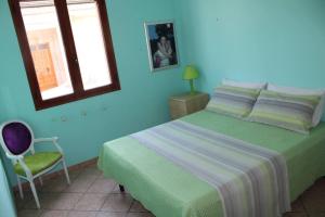 een slaapkamer met een groen bed en een stoel bij Villetta AmaMare in Torre Lapillo