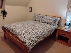 um quarto com uma cama e uma mesa de cabeceira com um relógio em Turfhill House em New Deer