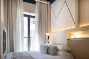 een slaapkamer met een bed met kussens en een raam bij Ikonik Jean Médecin in Nice