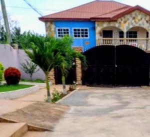 a blue house with a palm tree in front of it at Eliogemi Guest Room in Gbawe
