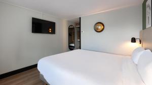 een slaapkamer met een wit bed en een tv bij Campanile NATURE - Toulouse Nord L'Union in LʼUnion +26 foto's