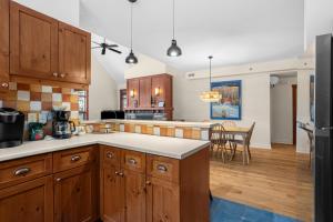 a kitchen with wooden cabinets and a dining room at Les Eaux 3BR, Sauna, Fireplace and Jacuzzi Access in Mont-Tremblant
