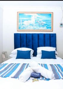 a large bed with a blue headboard and white pillows at African Oasis Cameroon in Somerset West +31 photos