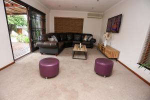 a living room with a leather couch and purple stools at African Oasis Cameroon in Somerset West