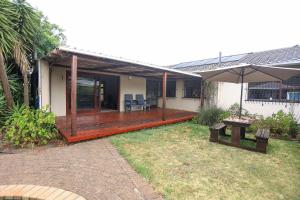 a house with a deck with a table and an umbrella at African Oasis Cameroon in Somerset West