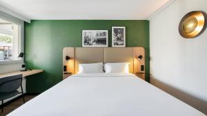 een slaapkamer met een groot bed en groene muren bij Campanile NATURE - Toulouse Nord L'Union in LʼUnion
