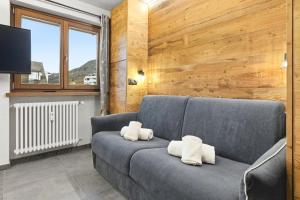een woonkamer met een blauwe bank met twee witte kussens bij Hostdomus-Mountain Nest in Sauze d'Oulx +6 foto's