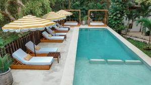 una piscina con lettini e ombrelloni di Mikasa Bacalar Hotel Boutique, Lagoon Front a Bacalar