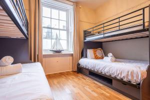 a bedroom with two bunk beds and a sailboat in a window at The Winkle - Elie in Elie