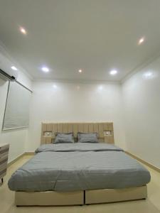 una camera con un grande letto su una parete bianca di شقق vip a Al Hofuf