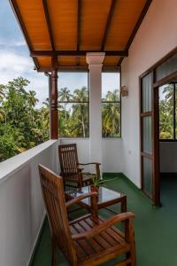 two chairs and a table on the porch of a house at Ayana wellness resort in Talpe