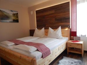 een slaapkamer met een groot bed met een houten hoofdeinde bij Ferienwohnung Hirtreiter in Lalling