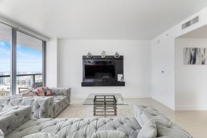 a living room with a couch and a tv at Spacious Luxury Apartment at Beachwalk Resort with Ocean Views and Private Foyer in Hallandale Beach +32 photos