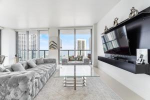a living room with a large couch and a flat screen tv at Spacious Luxury Apartment at Beachwalk Resort with Ocean Views and Private Foyer in Hallandale Beach