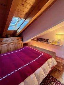 a bedroom with a purple bed in a attic at L'Atelier du Temps - Chalet Pompon in Cogne