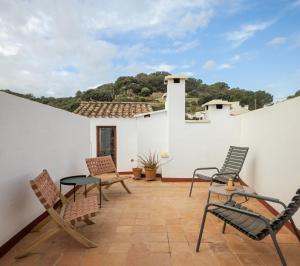 a patio with chairs and tables on a white wall at Ses Sucreres Small & Slow Hotel in Ferreries