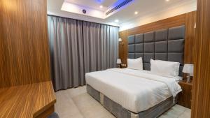a bedroom with a large bed with a large headboard at شقق المتألق الحديثة الفندقية in Dammam