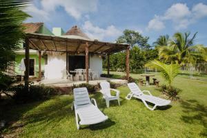 een groep stoelen en een huis met een prieel bij Luigi’s Glamping in Bacalar