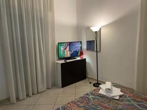Zimmer mit einem Bett, einem TV und einer Lampe in der Unterkunft Appartamento Premier in Gatteo a Mare