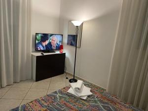 Zimmer mit einem TV, einem Bett und einer Lampe in der Unterkunft Appartamento Premier in Gatteo a Mare