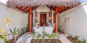 een badkamer met een bad en een rieten dak bij Hotel Whale Lagoon Maldives in Machchafushi