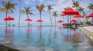 een resortzwembad met rode parasols en de oceaan bij Hotel Whale Lagoon Maldives in Machchafushi +30 foto's