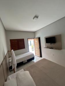 een slaapkamer met twee bedden, een tv en een raam bij Recanto Cangaço in Piranhas